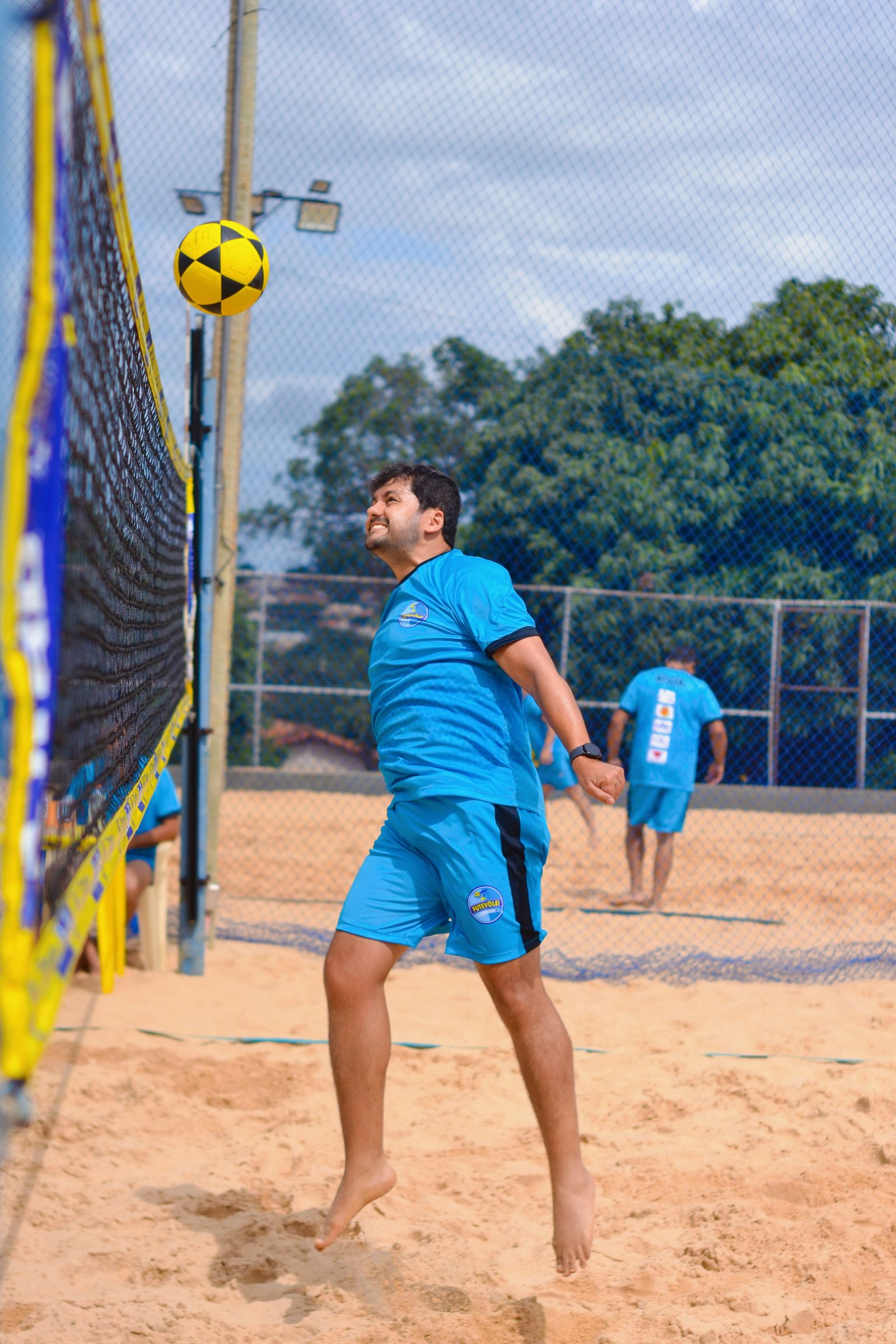 Jogador salta para alcançar a bola em uma partida de vôlei de praia